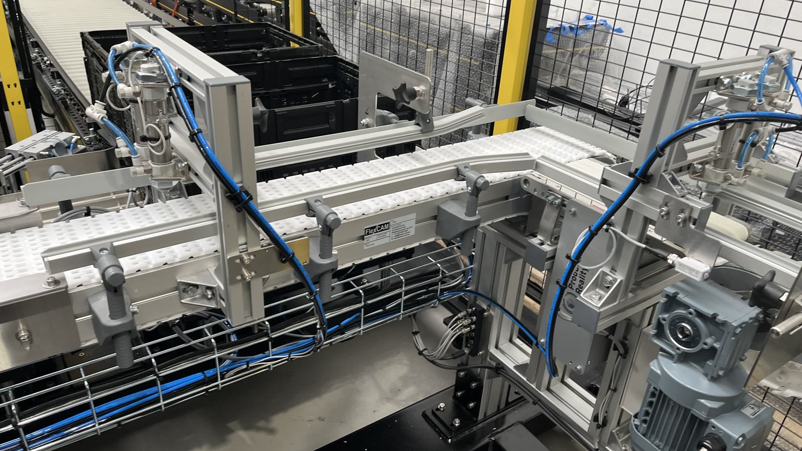 Food-packing cell showing conveyors, transfer mechanisms, pneumatic lines and machine guarding