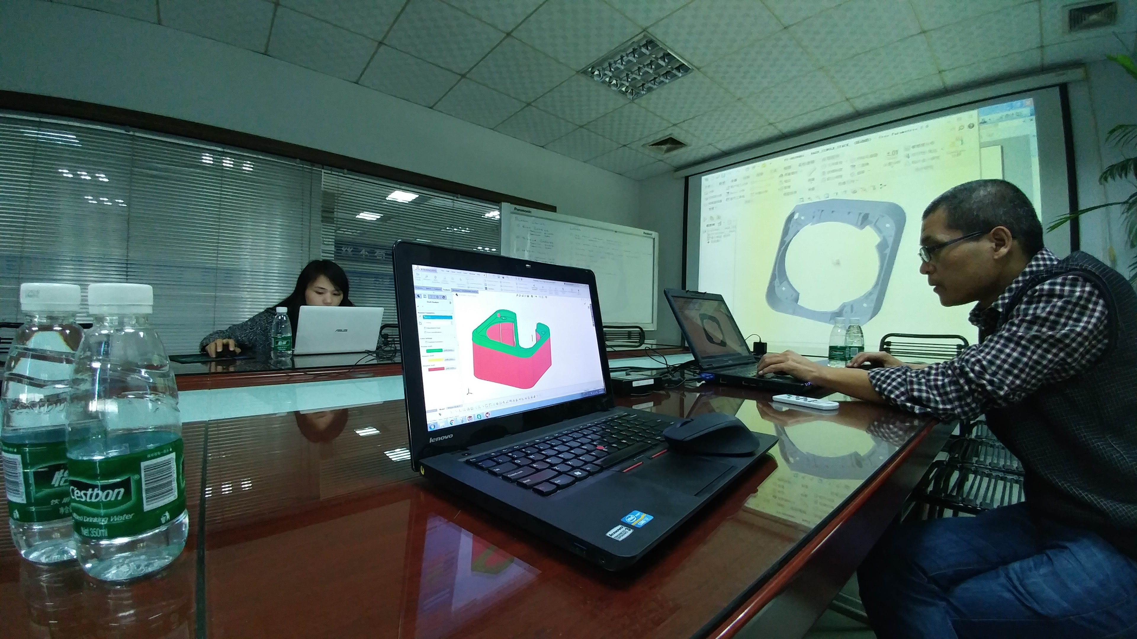 Engineering discussion with CAD models on laptops and a projection screen