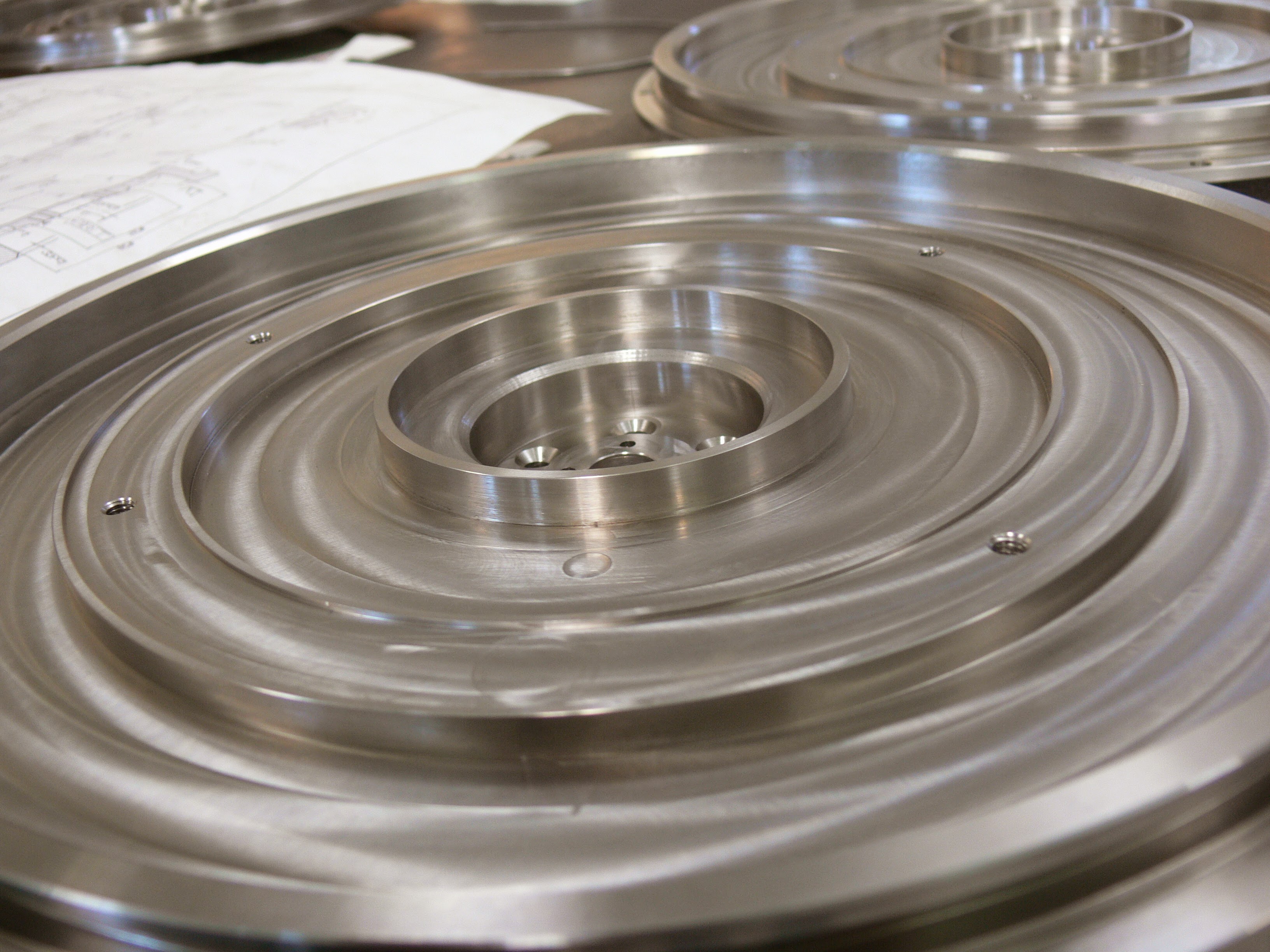 Circular machined metal plates with concentric features and central openings