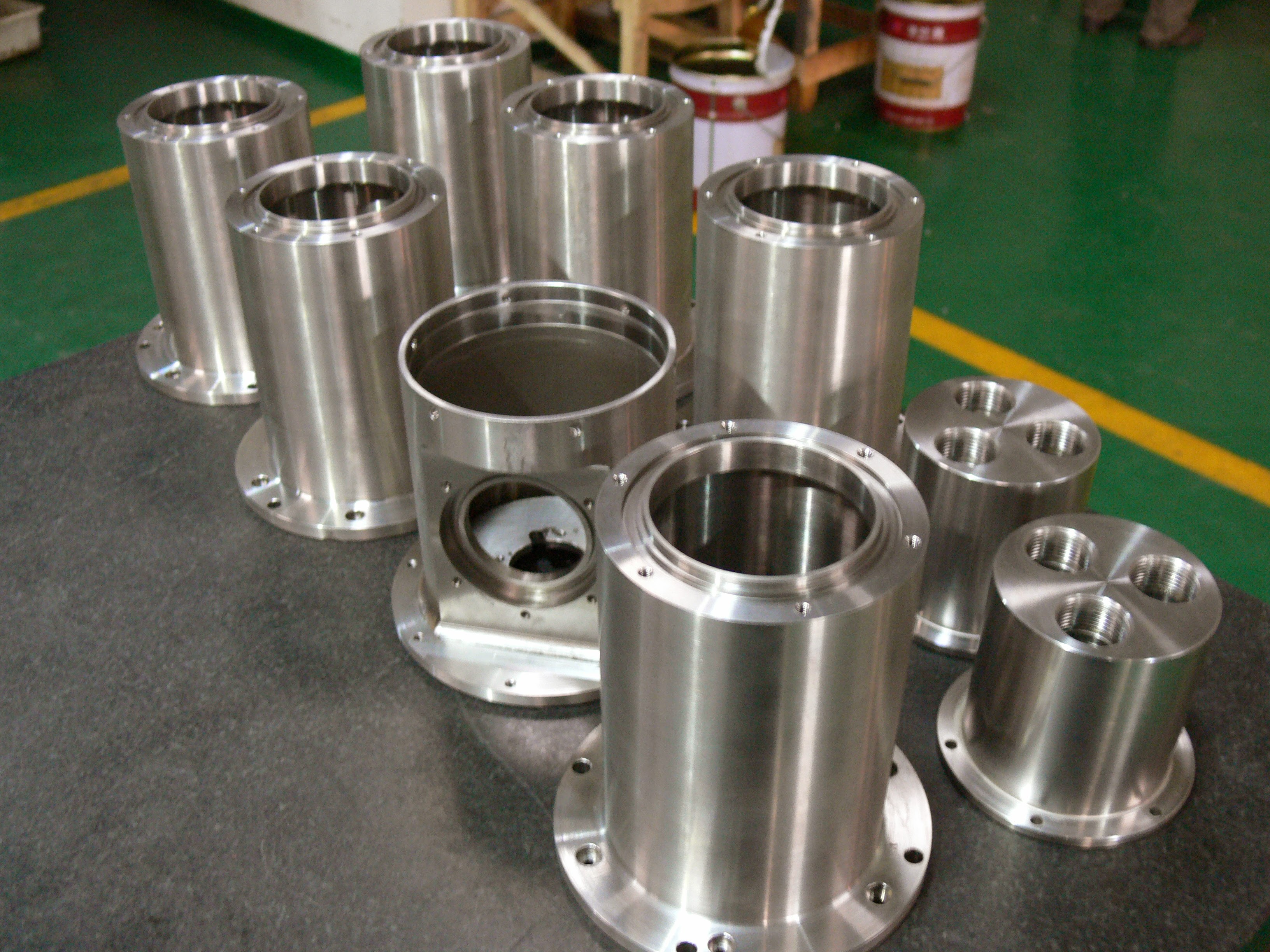 A group of cylindrical machined housings with flanges and threaded ports